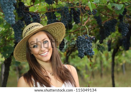 Beautiful country girl with blue eyes smiling. Grapes and vineyard as background