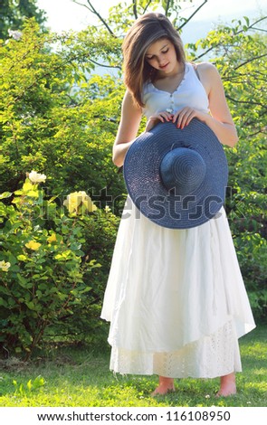 Romantic young girl with country white dress .Blue hat and daisy in her hands.
