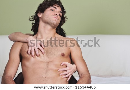Sexy young man  held in possessive hug .Bold gaze to the camera . Passion concept .