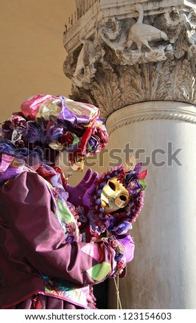 VENICE - FEBRUARY 16: Purple dressed joker mask reflected in a mirror  during Venice Carnival on February 16 , 2012 in Venice , Italy . An edict declared the day before Lent a public holiday.