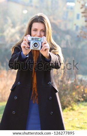 Beautiful girl with vintage camera in hand and joyful expression.Outdoor shot