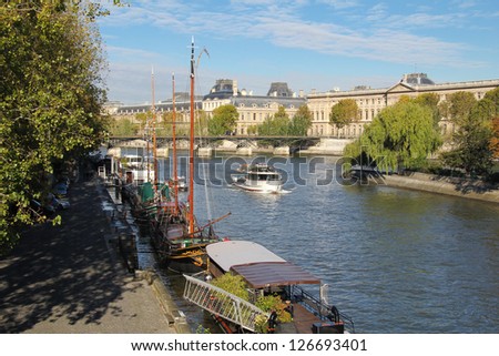 Seine river docks and boats with Louvre Museum in background. Paris in morning light