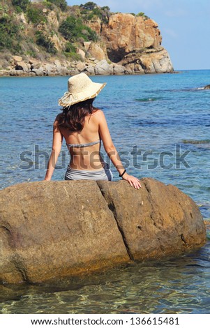 Young woman sitting on a rock by the sea . Relax and vacation conceptual