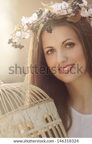Romantic portrait of a spring nymph with vintage bird cage.