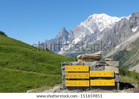 Mountain trail indications with Mont Blanc peak and ices in background