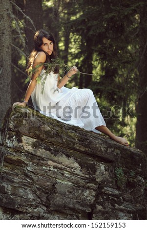 Portrait of a beautiful girl posing on forest rock. Fashion concept