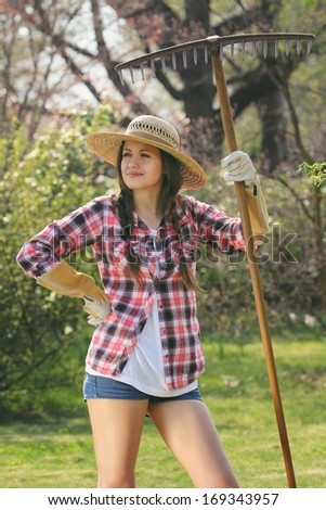 Funny expression on a beautiful  gardener posing with a rake . Garden and outdoor work