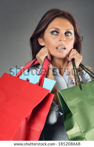 Shopping woman carrying bags . Grey backdrop