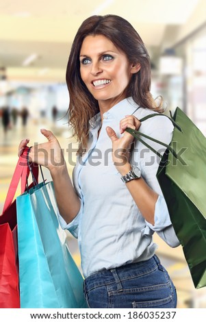 Shopping woman smiles  at department store with colorful bags in hands