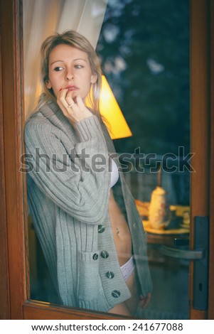 Beautiful woman looks outside the window . Loneliness and sadness concept