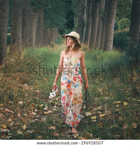 Beautiful woman walking barefooted in a meadow with trees