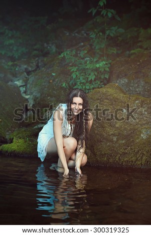 Smiling happy woman in a stream waters. Natural portrait