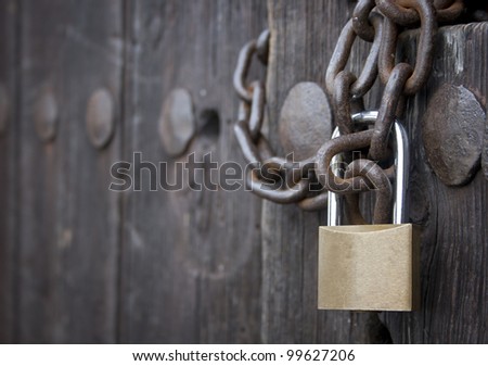 forefront of a padlock closing an old wooden door