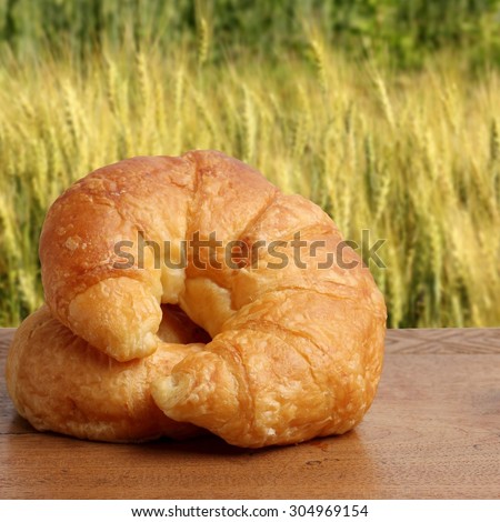 croissant bakery on teakwood table lighting and barley field background square format
