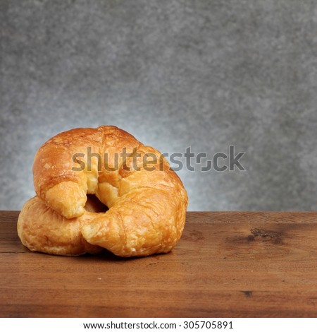 croissant bakery on teakwood table lighting and gray background square format