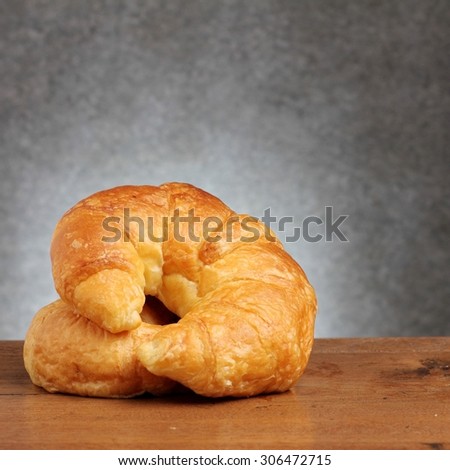 croissant bakery on teakwood table lighting and gray background square format