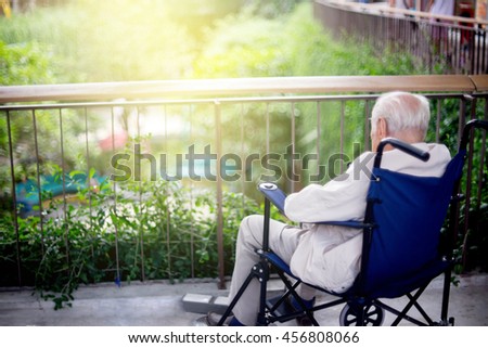 old man sit on wheelchair looking out to the park fill lonely waiting for take care