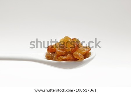 A handful of raisins in a white spoon on white background