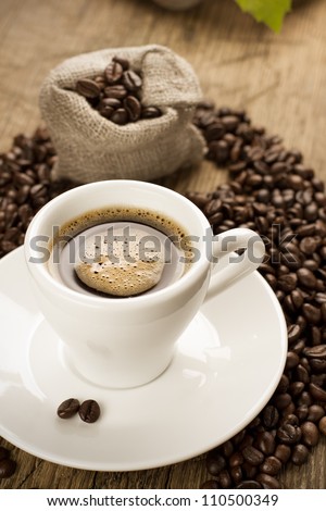 Small cup of strong coffee on a brown background with coffee beans