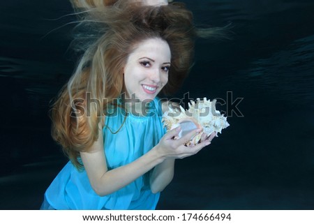 Woman smiling underwater in the pool with sea shell