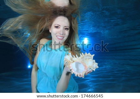 Woman smiling underwater in the pool with sea shell