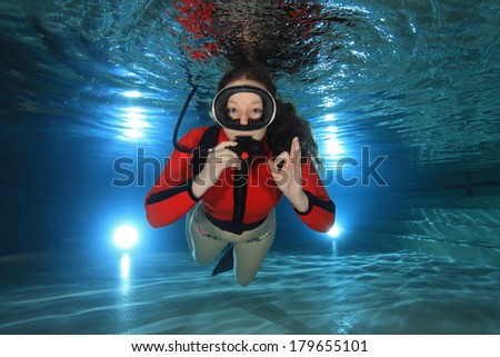 Scuba woman diving with red neoprene suit underwater in the pool