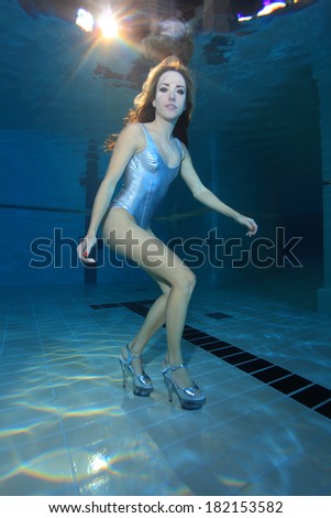 Underwater model with silver swimsuit and high heels underwater in the pool