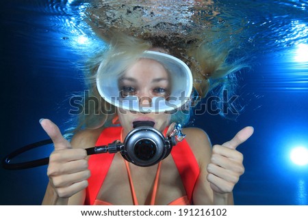 Happy female scuba diver show underwater signal