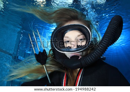 Scuba woman with black mask and spear gun diving underwater