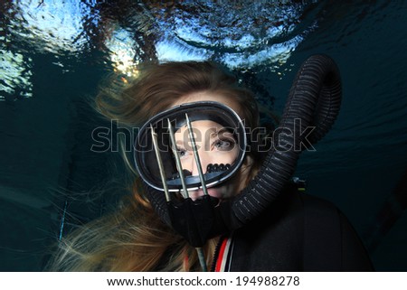 Scuba woman with black mask and spear gun diving underwater
