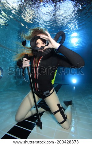 Scuba woman with black neoprene dive suit and spear gun underwater