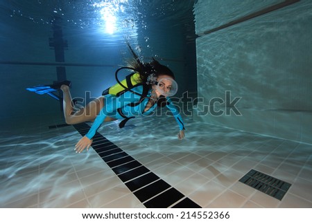 Female scuba diver with lycra suit swimming underwater in the pool