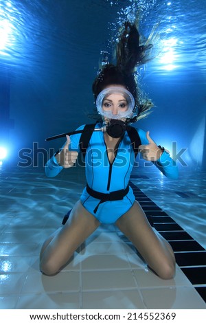 Female scuba diver with lycra suit show hand signal underwater in the pool