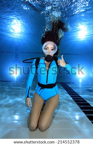 Female scuba diver with lycra suit show hand signal underwater in the pool