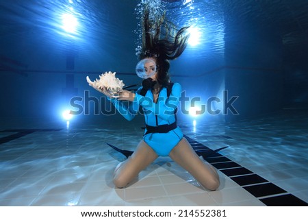 Scuba woman with lycra dive suit and sea shell underwater in the pool
