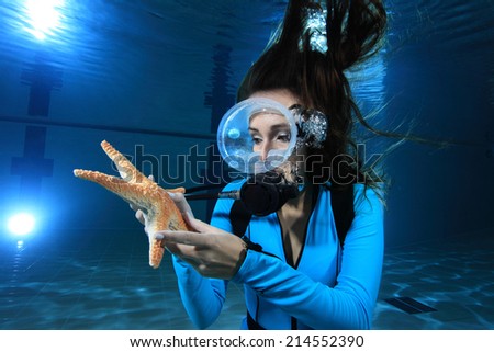 Scuba woman with lycra dive suit and sea star underwater in the pool