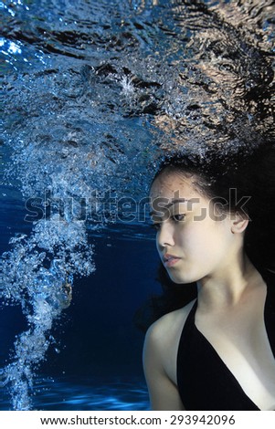 Young woman underwater with air bubbles