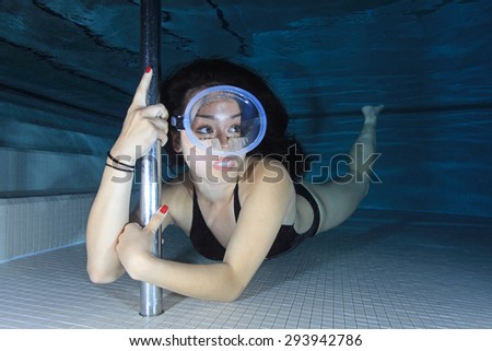 Female diver with one-piece swimsuit and dive mask posing underwater in the pool