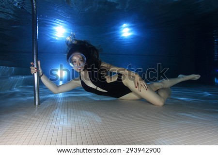 Female diver with one-piece swimsuit and dive mask posing underwater in the pool