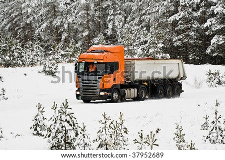 Dump-body truck on the road in winter woods
