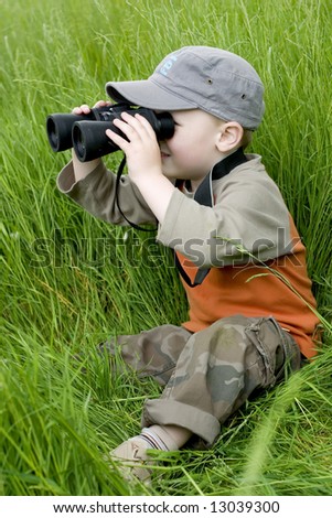 little boy in high grass searching for something