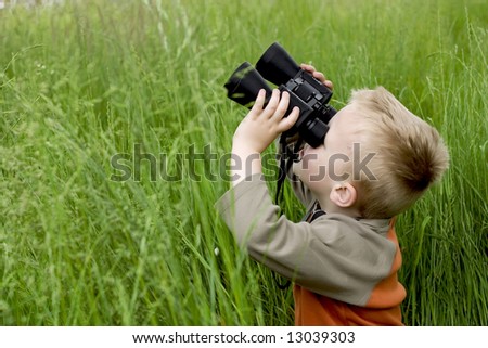 little boy in high grass searching for something