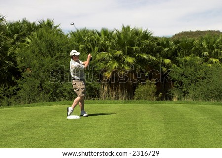 Golfer turning after the shot from the tee box. Golf club is still in motion after the shot.