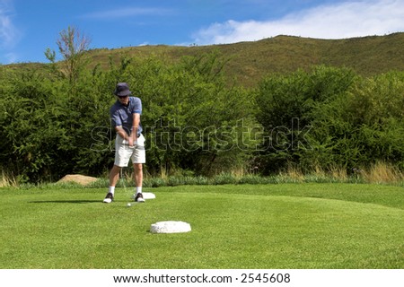 Golfer hitting the ball from the tee box. Hands and club are in motion.