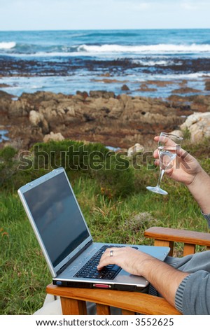 Young businessman working on his laptop and drinking water outside