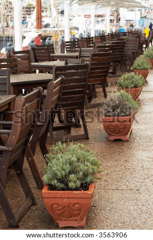 Wooden tables and chairs under umbrellas in the outside restaurant