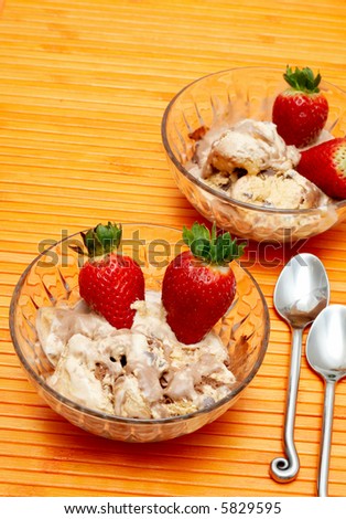 Chocolate ice-cream and strawberries in crystal bowls on orange background