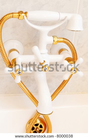 Beautiful gold and white decorative tap in a tiled bathroom