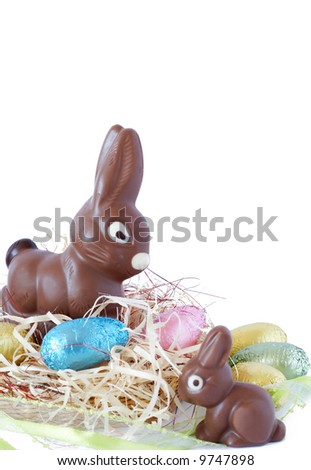 Assortment of chocolate Easter eggs wrapped in colorful paper with chocolate bunnies on straw