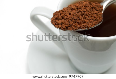 Closeup of instant coffee granules in silver spoon on white cup. Macro shot - shallow depth of field